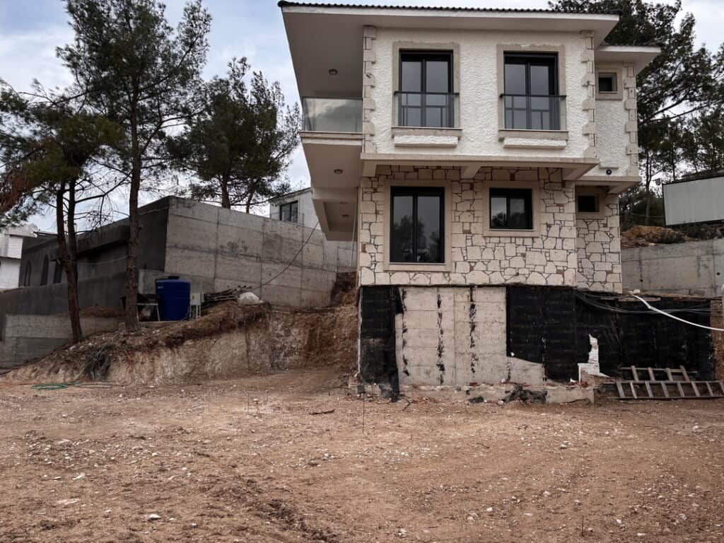 Çamlıbel Villası imalat öncesi: iki katlı taş kaplamalı villa ve düzenlenmemiş bahçe